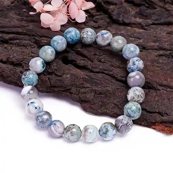 Multicolored beaded bracelet on a wooden surface with pink flowers.